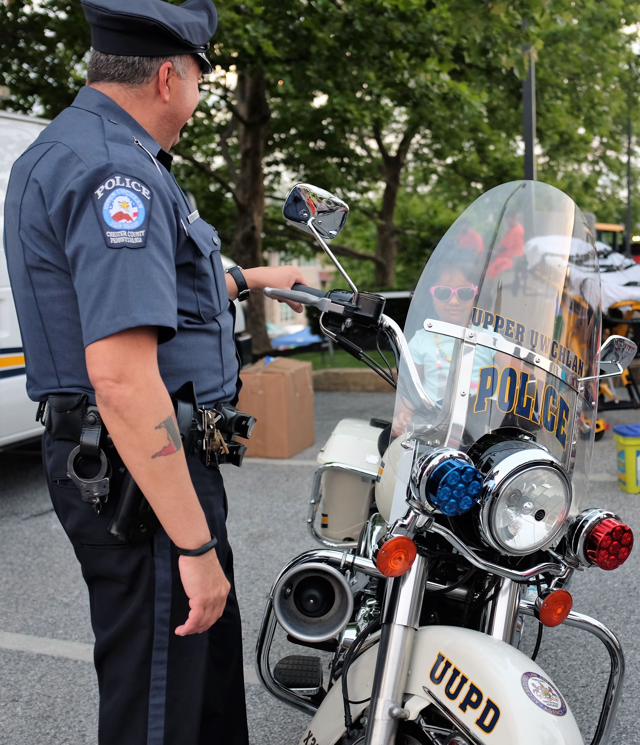 Officer looks on as young resident sits on UUPD motorcycle